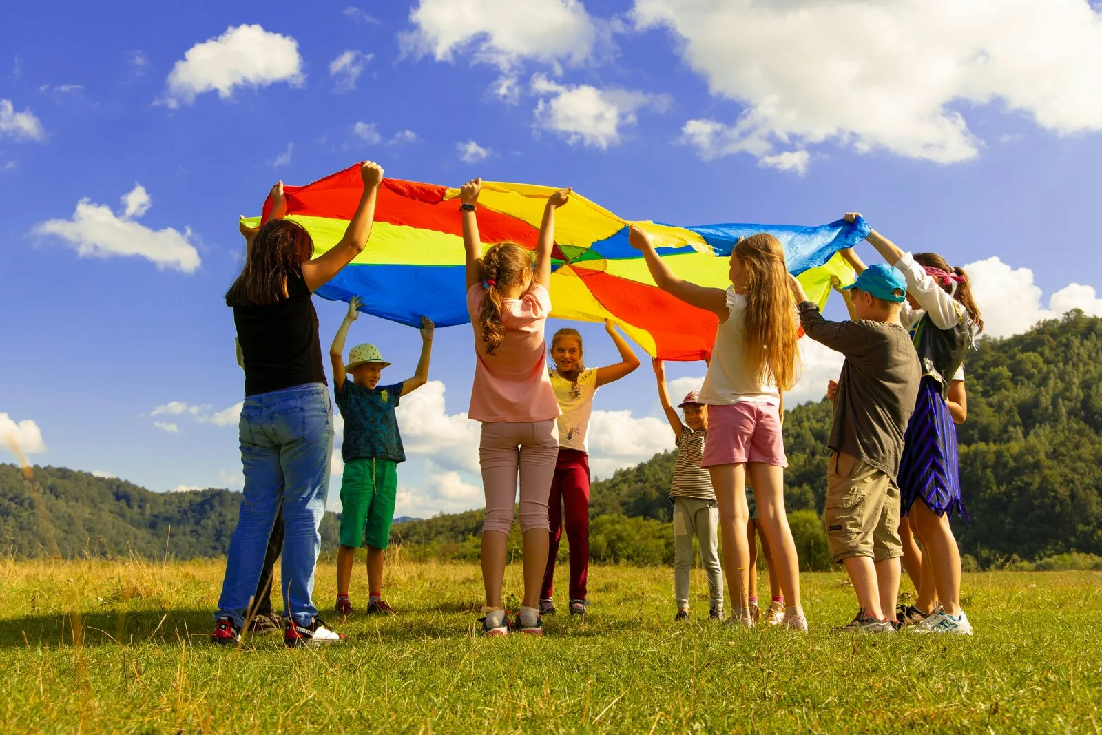 Children playing outdoors with a colorful parachute