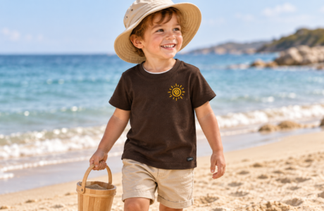 Toddler wearing a brown UPF 50+ sun-protection T-shirt while playing at the beach
