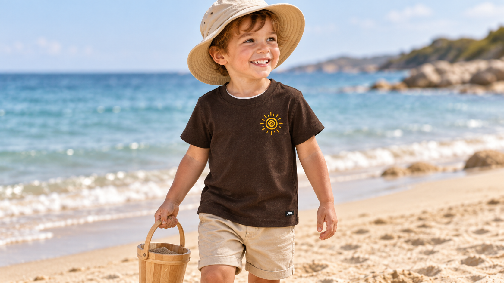 Toddler wearing a brown UPF 50+ sun-protection T-shirt while playing at the beach